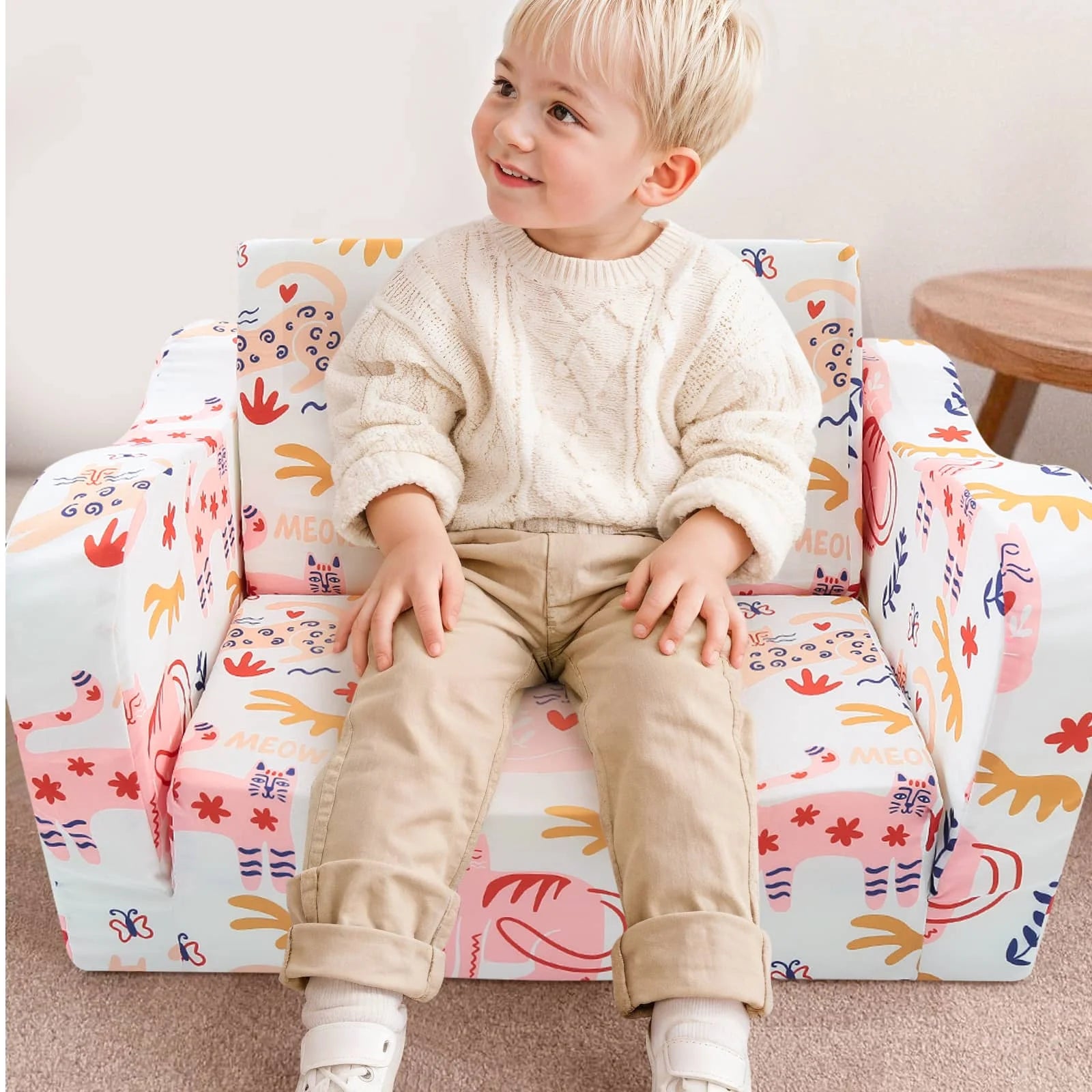 A boy sitting in Glowsofa's children's couch chair with Cat patterns