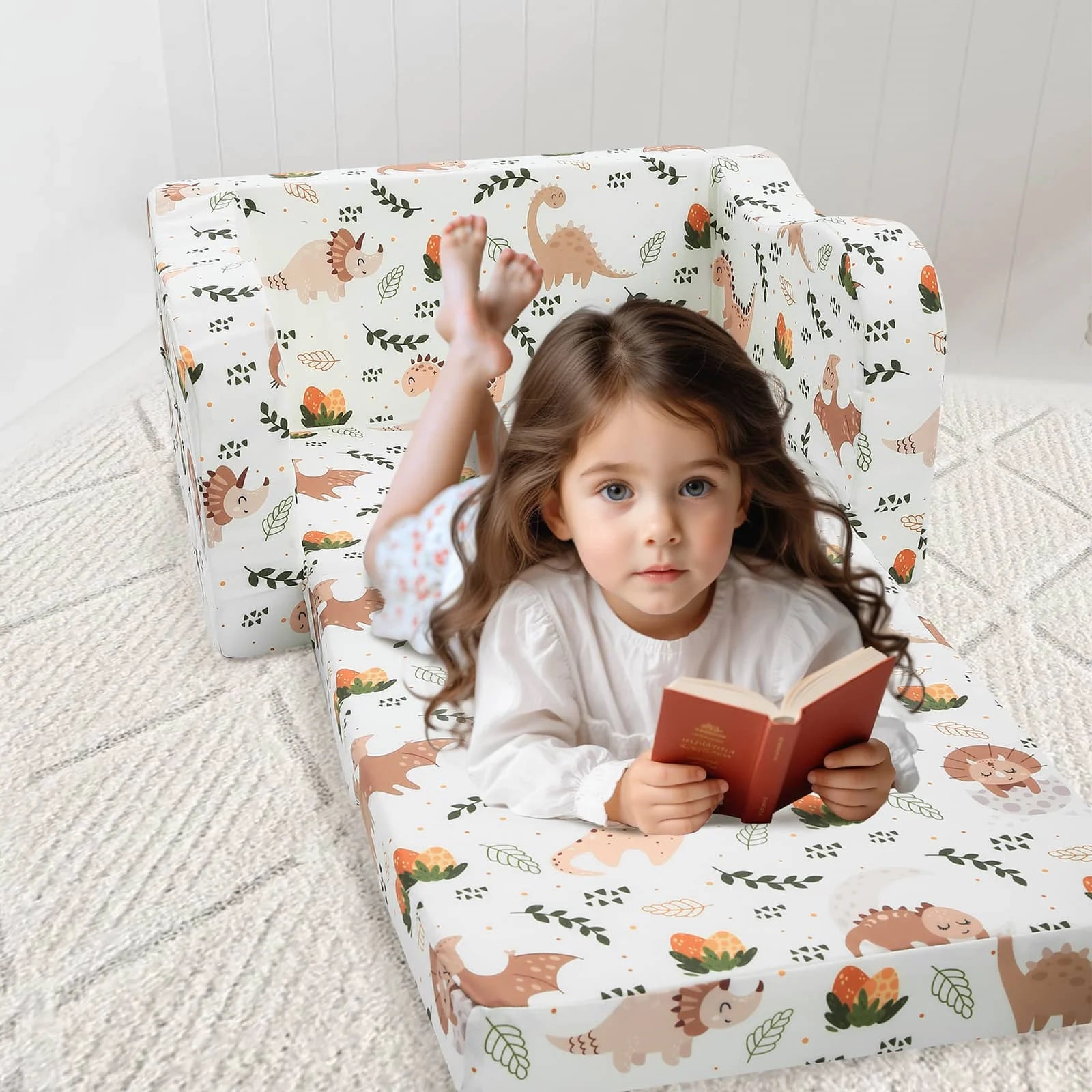 A little girl lying on an unfolded Glowsofa's Children's fold out sofa with Dinosaur patterns