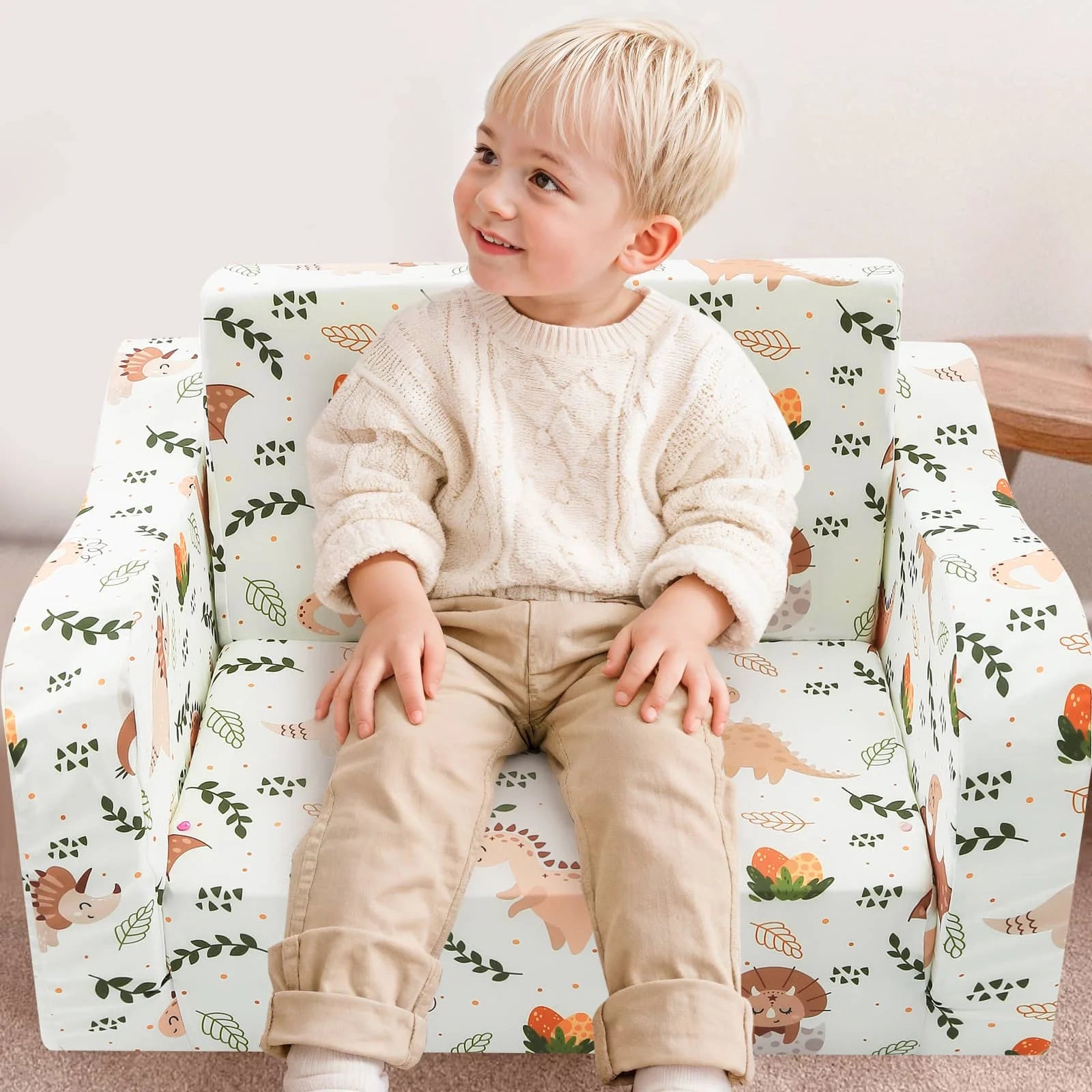 A boy sitting in Glowsofa's children's couch chair with Dinosaur patterns 