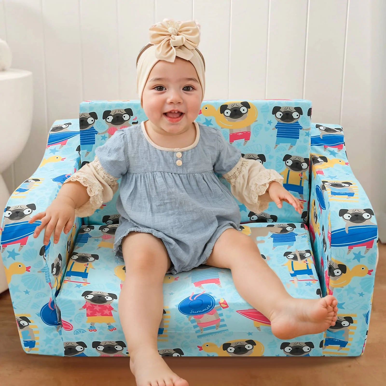 A baby sitting in Glowsofa's children's couch chair with Dog patterns 