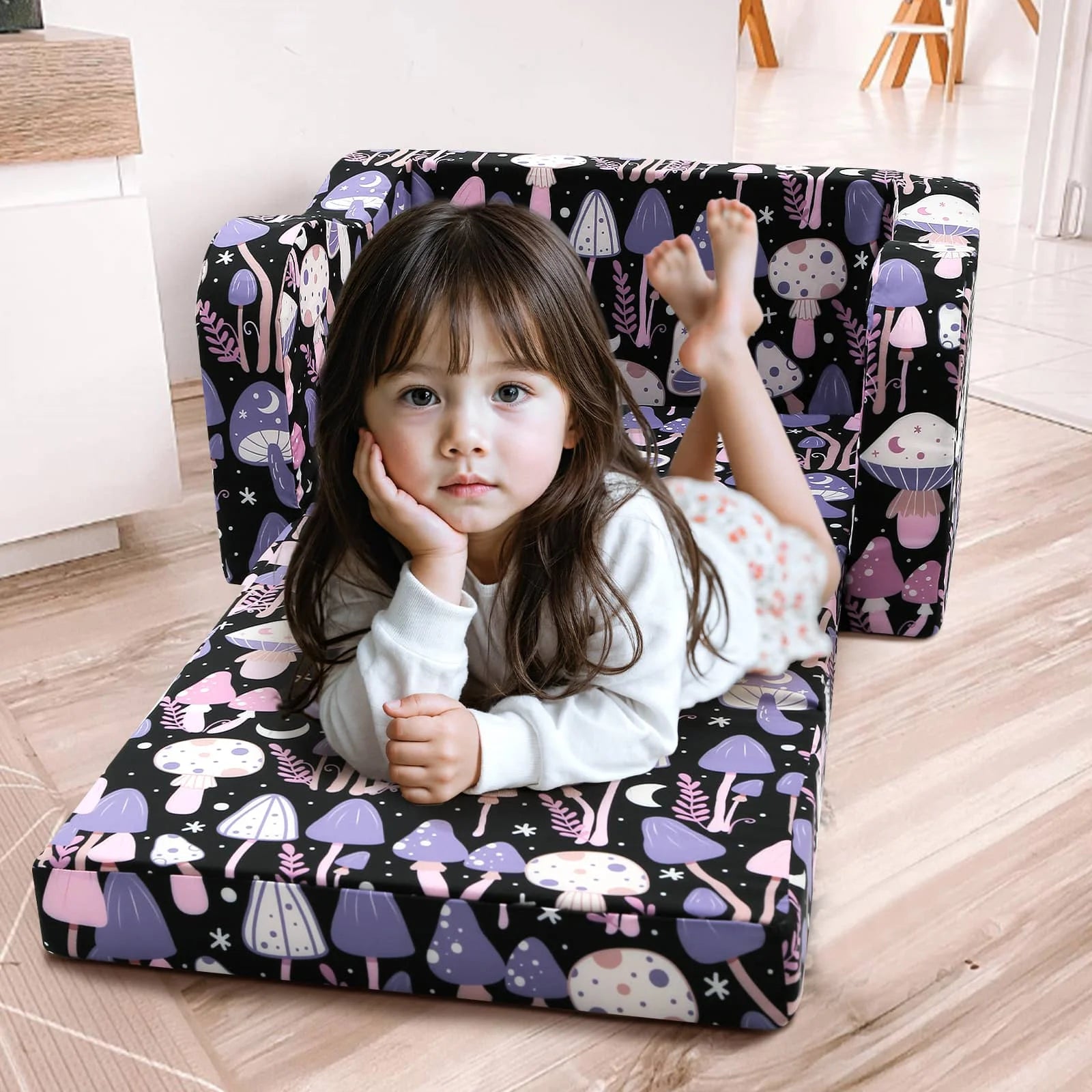 A little girl lying on an unfolded Glowsofa's Children's fold out sofa with Mushroom patterns