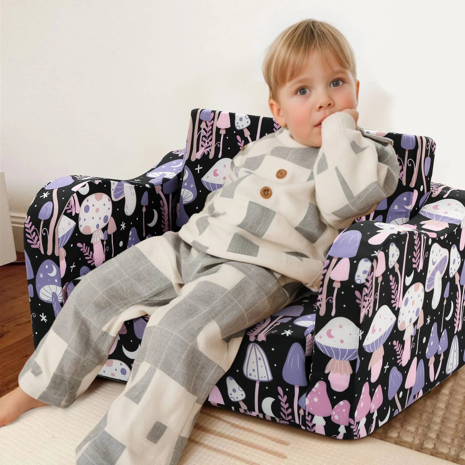 A boy sitting in Glowsofa's children's couch chair with Mushroom patterns 