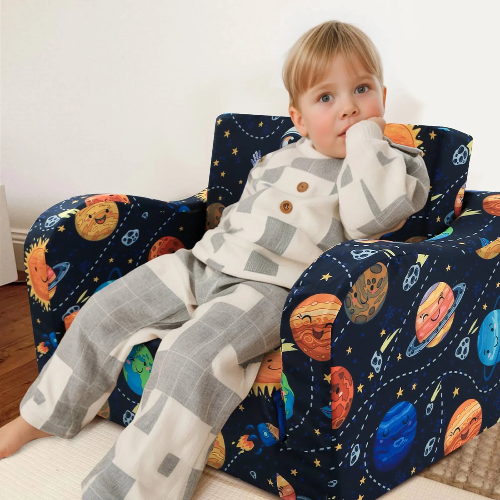 A boy sitting in Glowsofa's children's couch chair with Astronaut patterns 