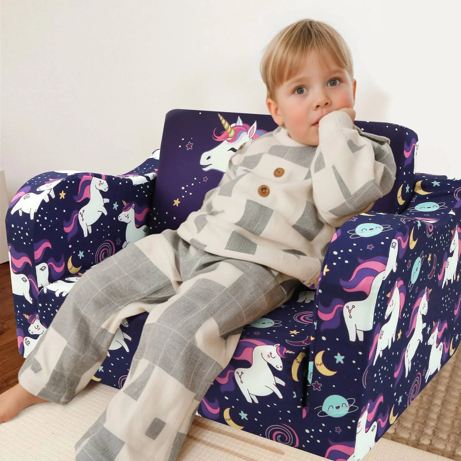 A boy sitting in Glowsofa's children's couch chair with Unicorn patterns 